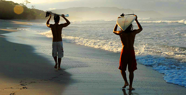 Surfers carrying their boards to the sea in Costa Rica