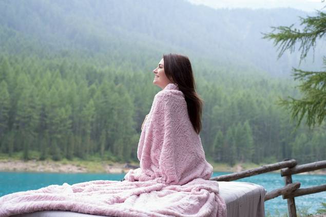 Woman sitting overlooking lake and forests happy