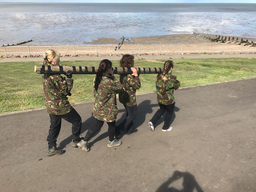 Women carrying logs as part of a training exercise at GI Jane Bootcamp