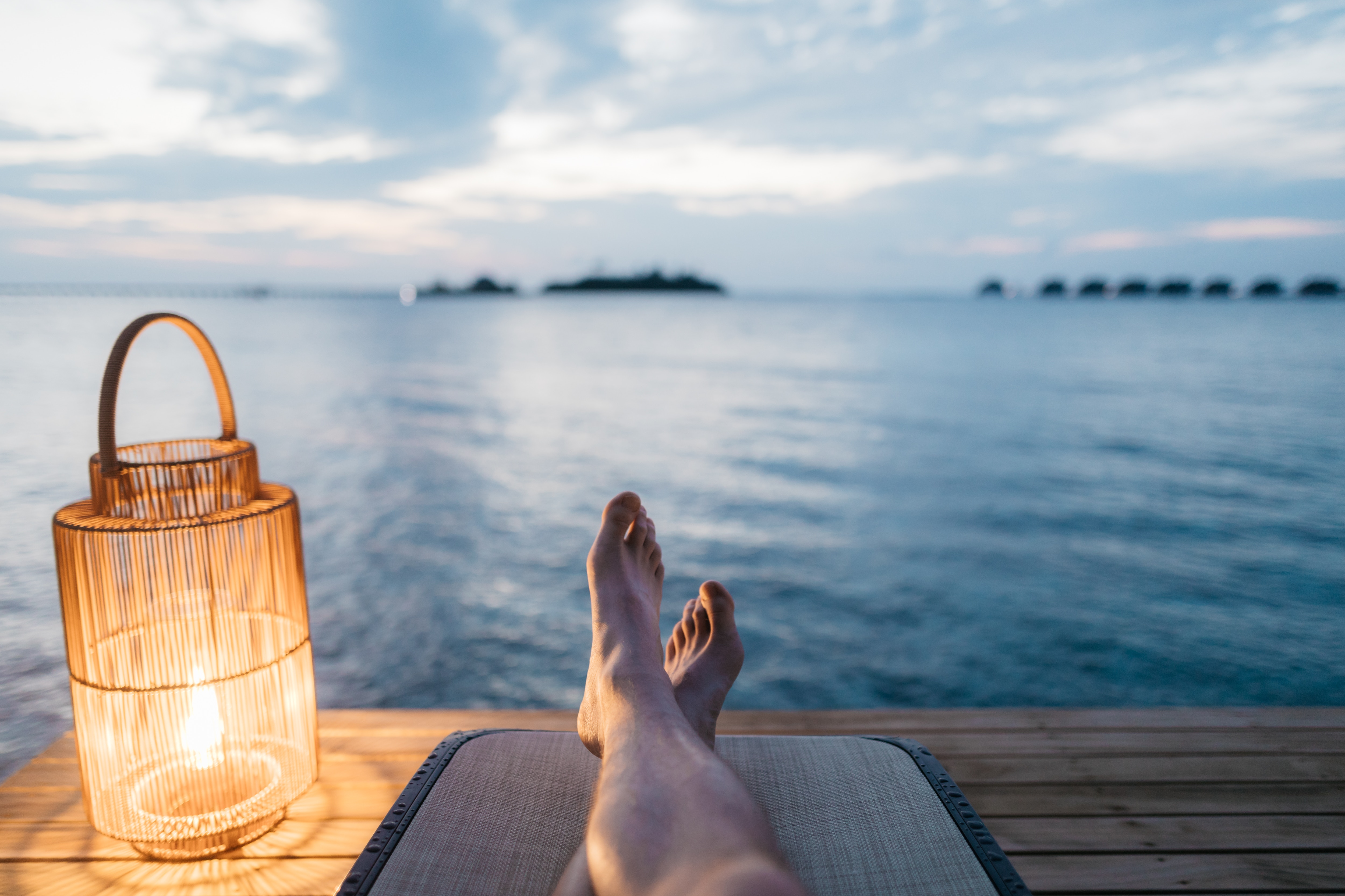 Person relaxing by the sea with their feet up and a candle lit