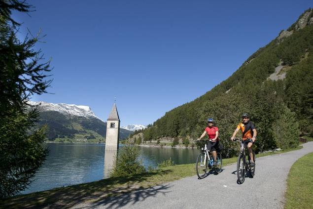 Couple cycling by the water and mountains