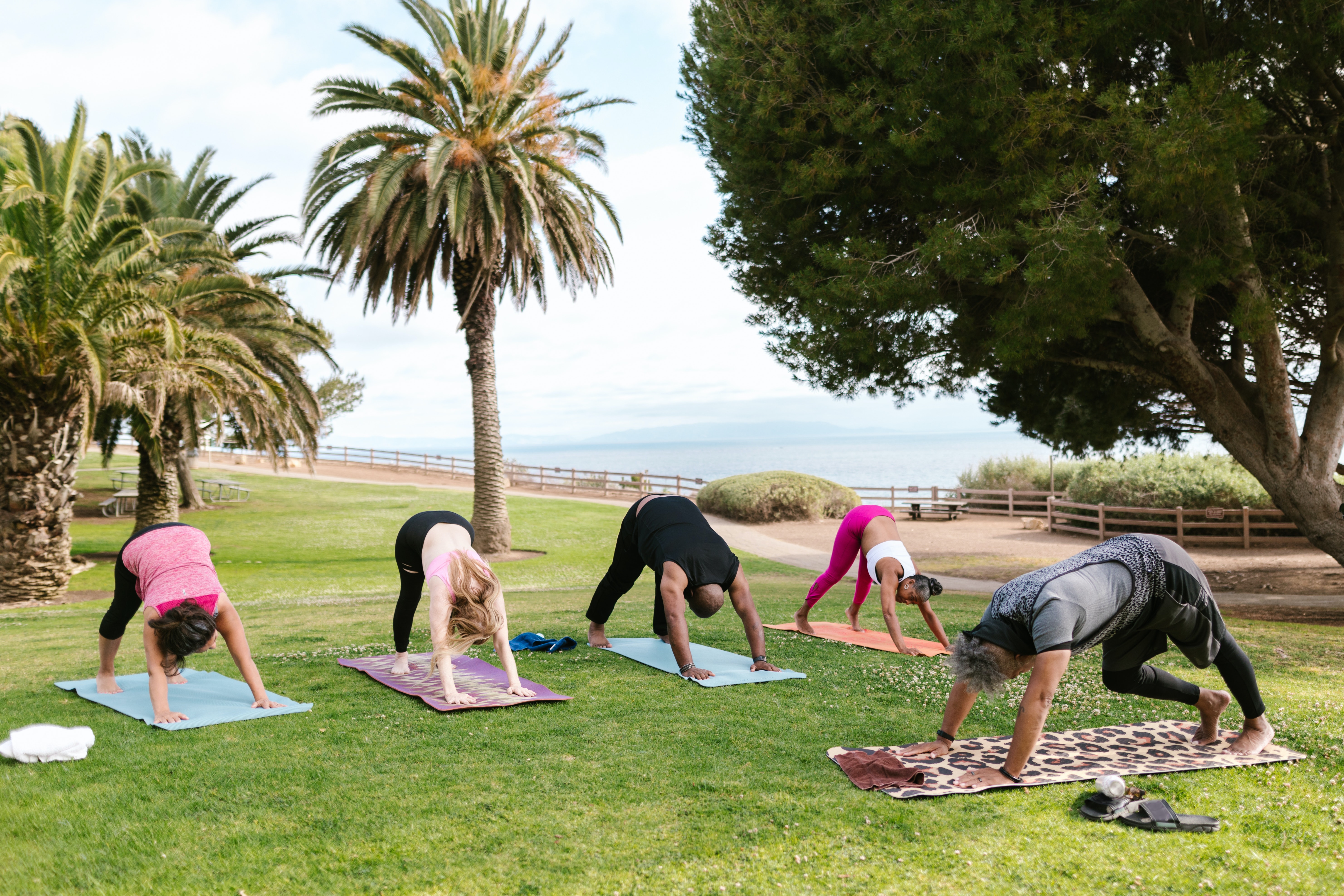 A class being taught yoga by the beach