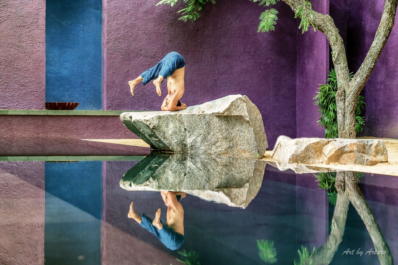 Man doing a headstand on a rock at The Barai Spa in Thailand