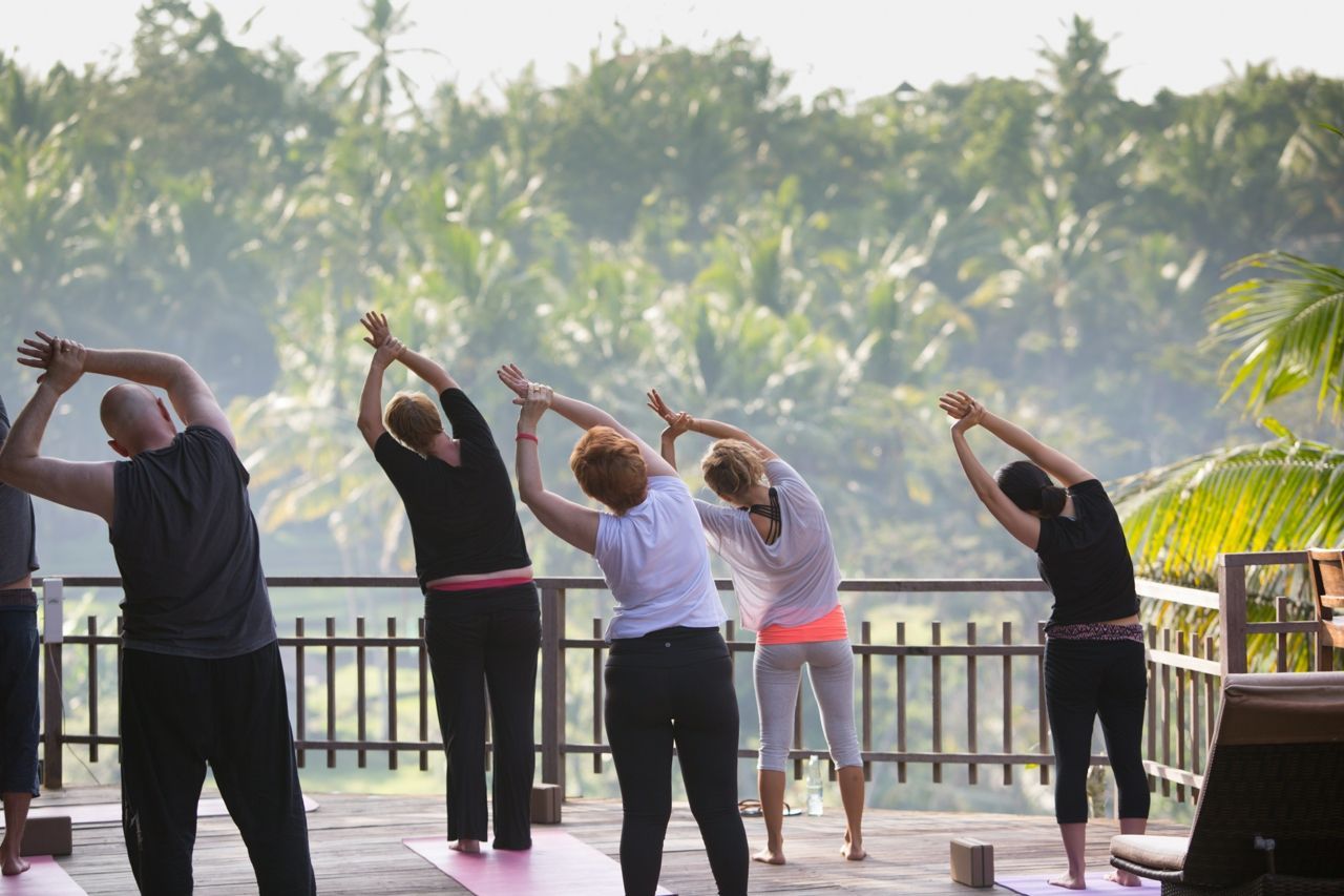 A group of people practicing yoga outdoor in a calm atmosphere