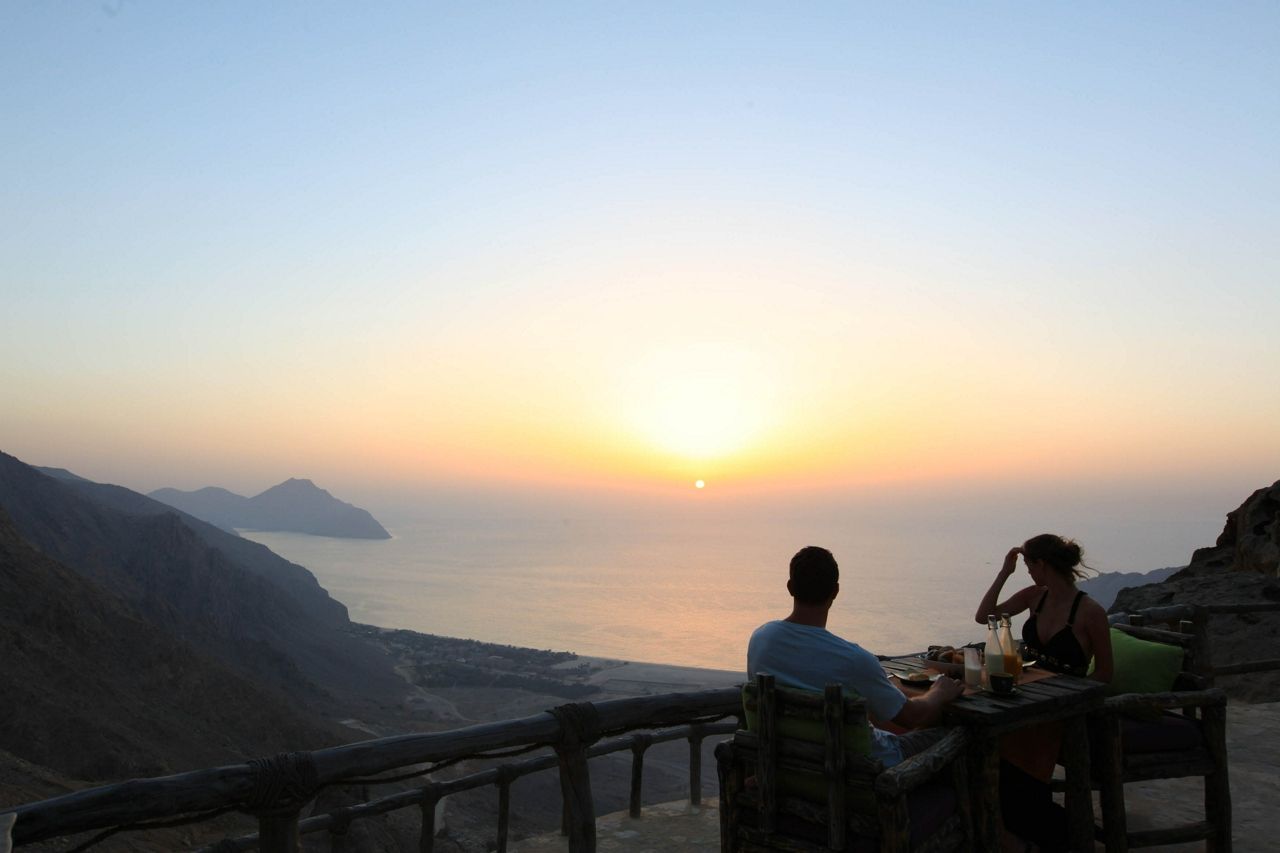 Couple eating dinner at Six Senses Zighy Bay overlooking a fantastic view on a wellness retreat