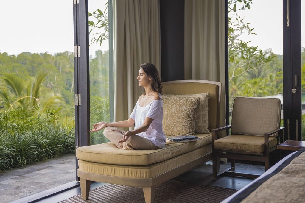 Woman meditating in her hotel room. meditation is great for both your physical and mental health