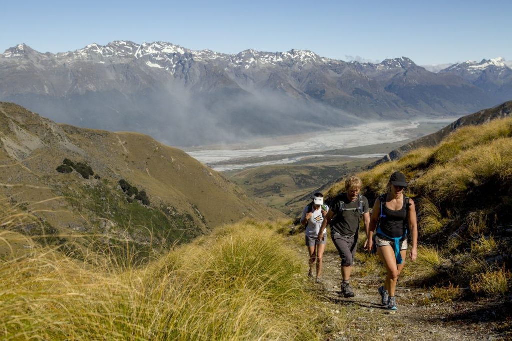 Hikers trek across rope-bridge with mountains in the background