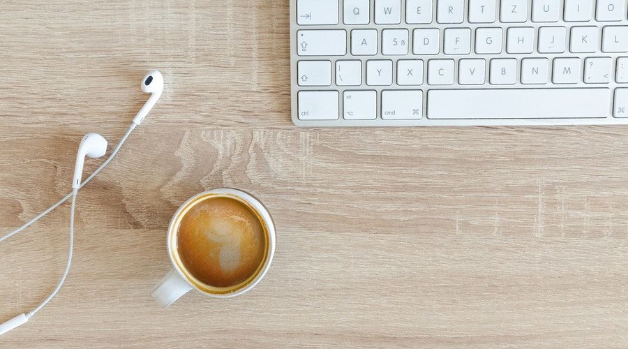 Computer keyboard with coffee and earphones