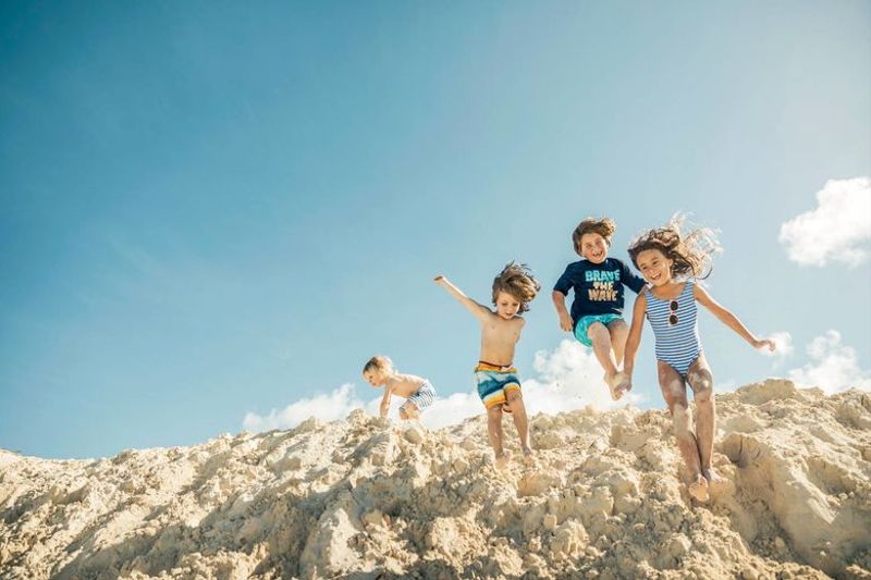 Children playing on sand dunes together