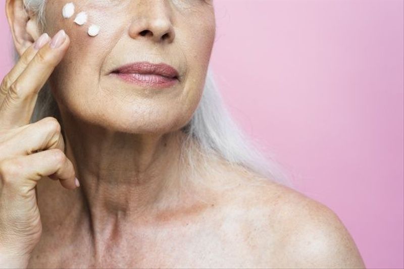 Woman applying cream on her face