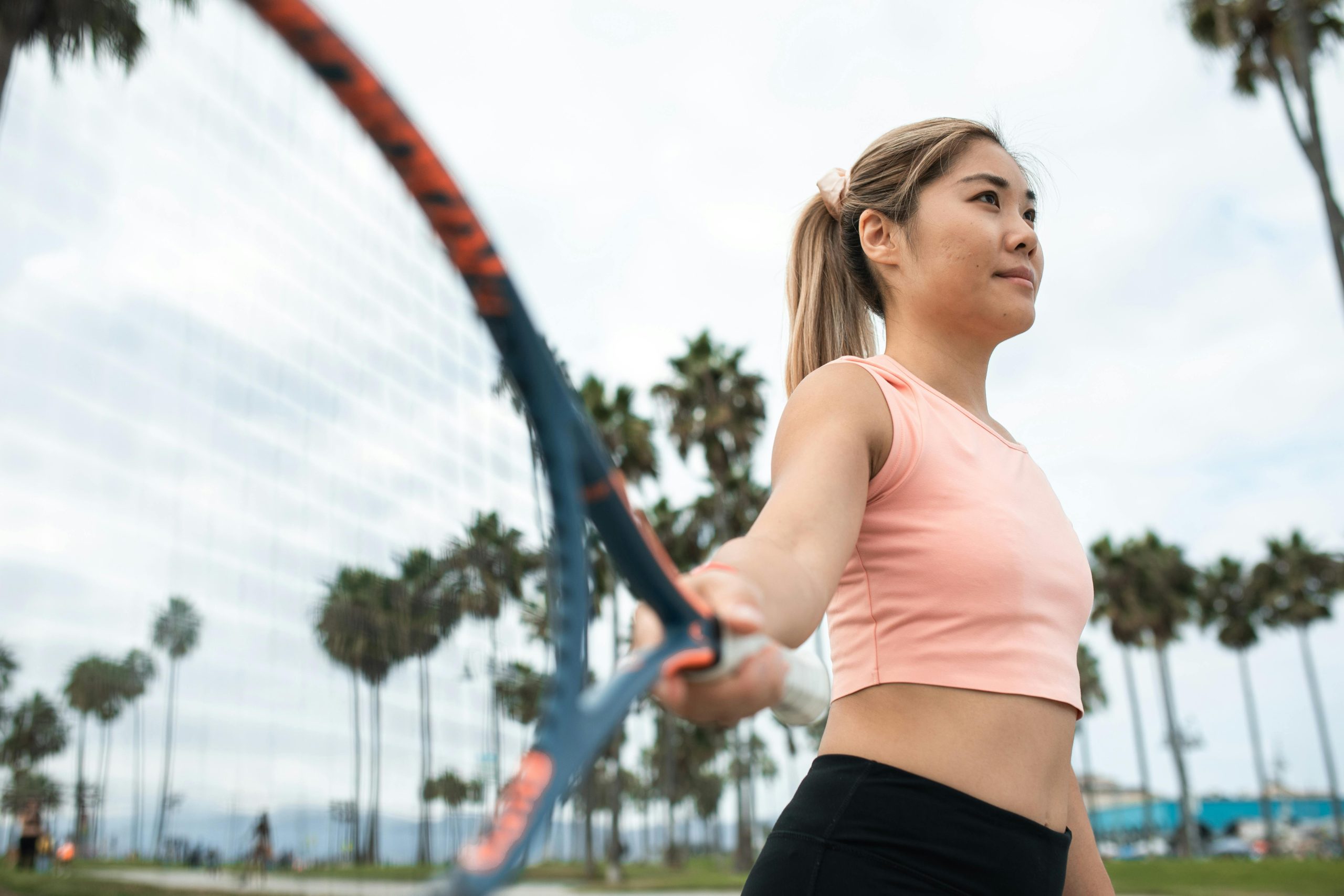 Woman playing tennis in front of palm trees