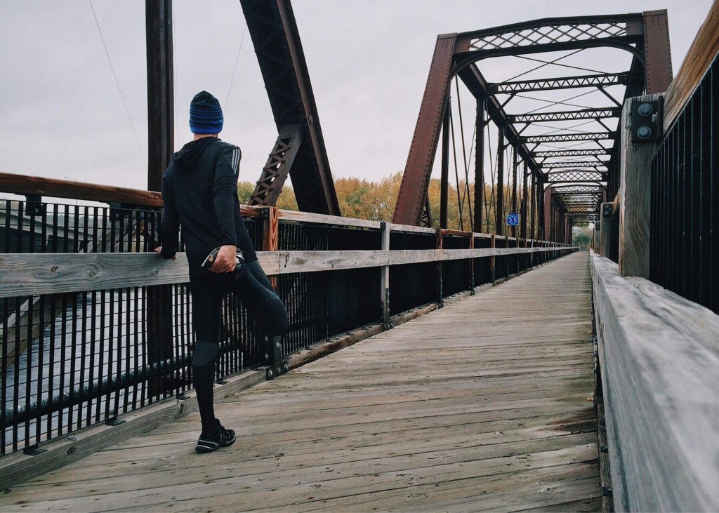 Man stretching on a bridge