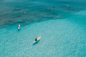 Aerial view of surfers enjoying crystal clear waters in Hawaii, perfect for surf enthusiasts.